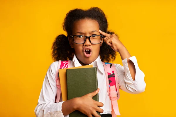 Dispiaciuto africano scuola ragazza holding libri su giallo sfondo, studio — Foto Stock
