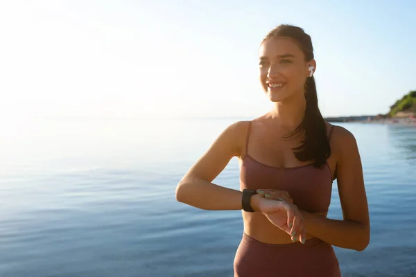 Feliz mujer sana corriendo en la playa, usando rastreador — Foto de Stock