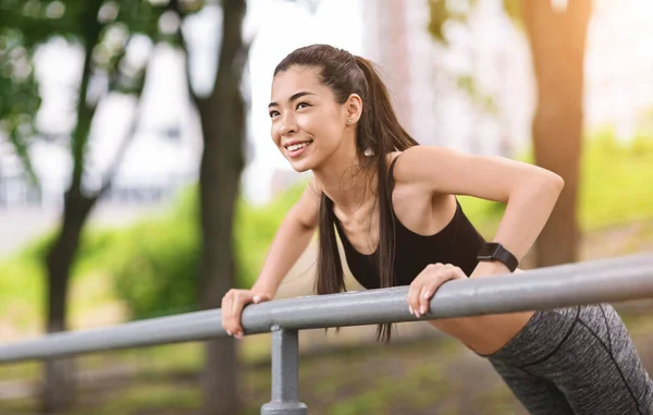 Allenamento all'aperto. Sporty ragazza asiatica facendo push up con corrimano come colonna portante — Foto Stock