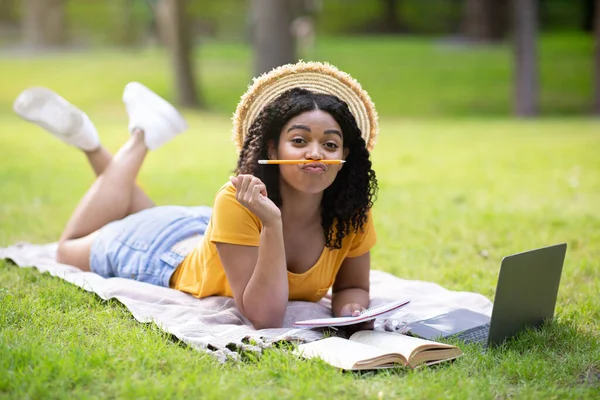 在公园用笔记本电脑学习的时候，漂亮的黑人女孩很傻，还在做鬼脸 — 图库照片
