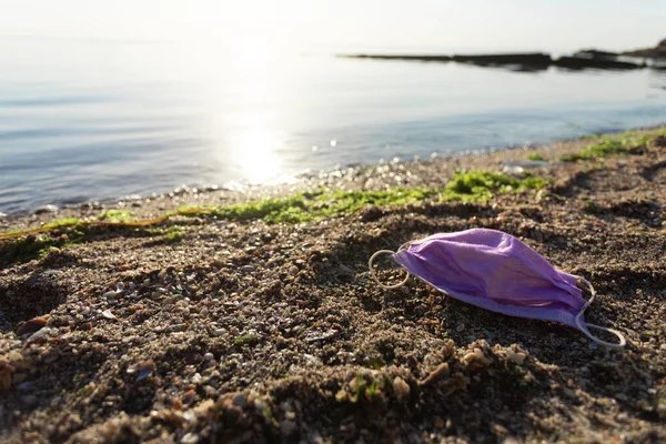 Пустая медицинская маска, лежащая на загрязненном пляже на открытом воздухе, свободное место — стоковое фото