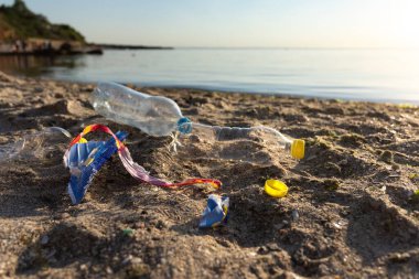 Plastik çöplerle kirlenmiş plaj Kum suyunun yanında yatıyor