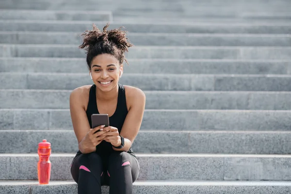 African american girl in sportswear, with wireless headphones and fitness tracker — Stock Photo, Image