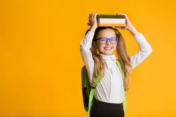 Happy School Girl drží knihy na hlavě pózování ve studiu — Stock fotografie