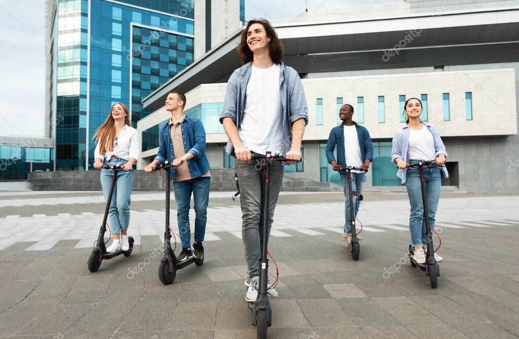 Five friends having nice ride on motorized kick scooters