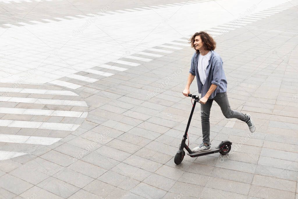 Handsome guy having pleasant ride on electric kick scooter