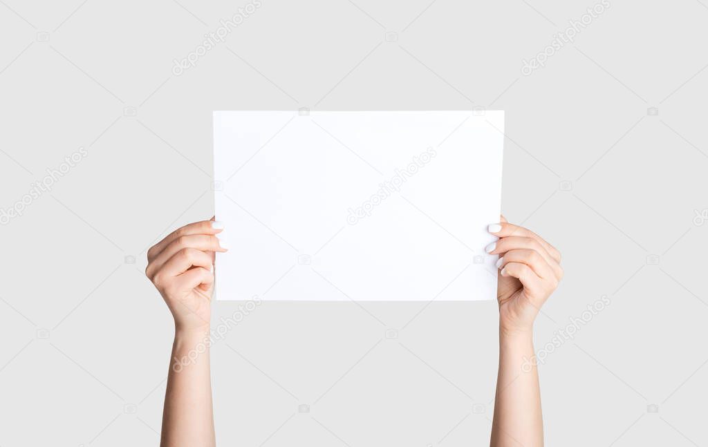 Closeup of young girl holding empty sheet of paper on white background, mockup for your design