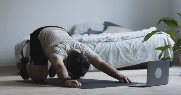 Jongeman beoefenen van yoga, kijken naar tutorial op laptop — Stockvideo