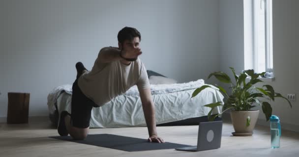 Szakállas férfi gyakorló szőnyegen laptop otthon — Stock videók