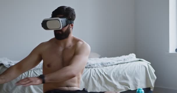 Młody mężczyzna w słuchawkach VR ćwiczący w domu — Wideo stockowe