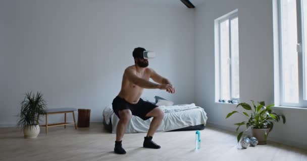 Aktivní muž v brýlích VR dřepí doma — Stock video