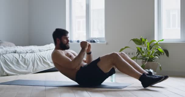 Young guy with naked torso doing abs exercise at home — Stock Video