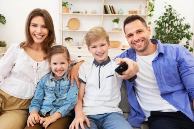 Aile TV izliyor Kanalları değiştiriyor Evdeki koltukta oturuyor