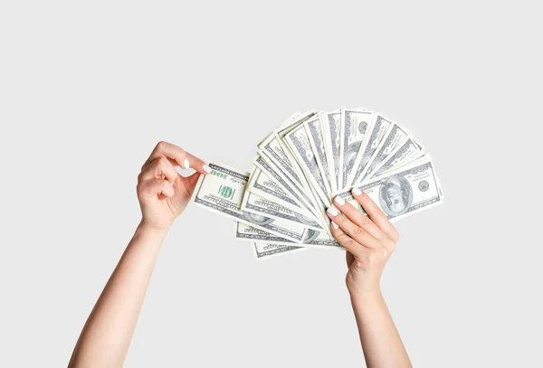 Milenial dama tirando de billete de cien dólares de fan del dinero sobre fondo blanco, primer plano — Foto de Stock