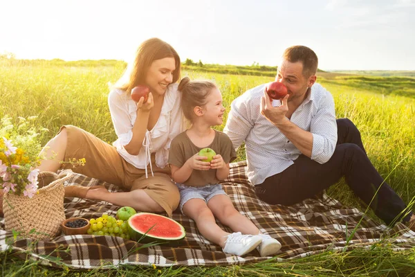 Счастливая семья играет с яблоками на пикнике на открытом воздухе — стоковое фото
