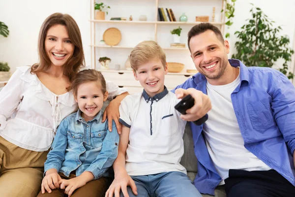 Família assistindo TV comutando canais sentados no sofá em casa — Fotografia de Stock