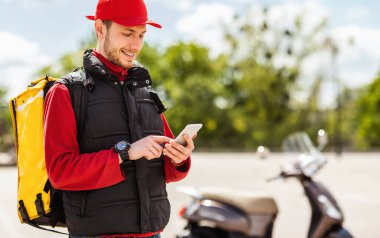 Smartphone kullanan teslimatçı Scooter 'la yiyecek getiriyor.