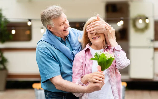 Sorpresa inesperada. Hombre mayor cerrando los ojos de sus esposas y dándole flores en el camping —  Fotos de Stock