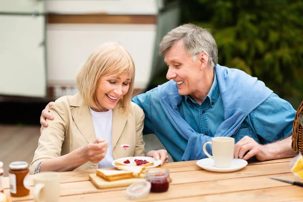 Happy senior couple having toasts with jam and coffee for breakfast at campground — Stock Photo, Image