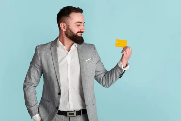 Glimlachend bedrijf werknemer toont credit card op blauwe achtergrond, vrije ruimte — Stockfoto