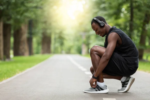 Schwarzer Sportler bindet sich vor dem Training die Schuhe — Stockfoto