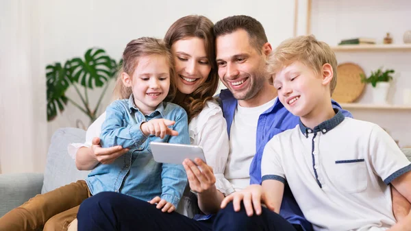 Family Of Four Using Smartphone Sitting On Couch At Home — Stock Photo, Image