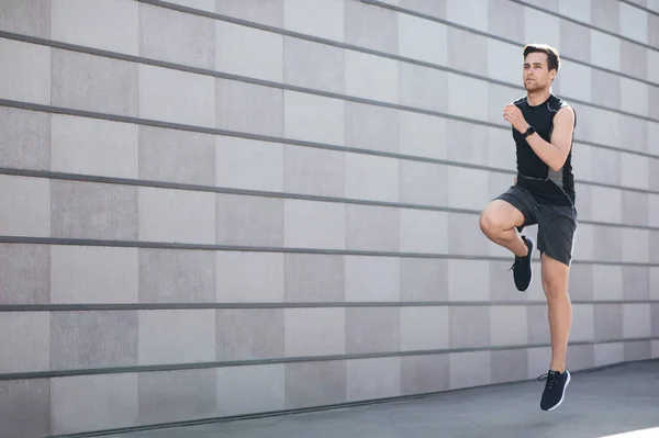 Oefening voor gezondheid buiten. Jongeman met fitness tracker springen — Stockfoto