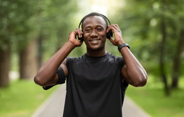 Feliz deportista negro poniendo auriculares inalámbricos en su cabeza — Foto de Stock