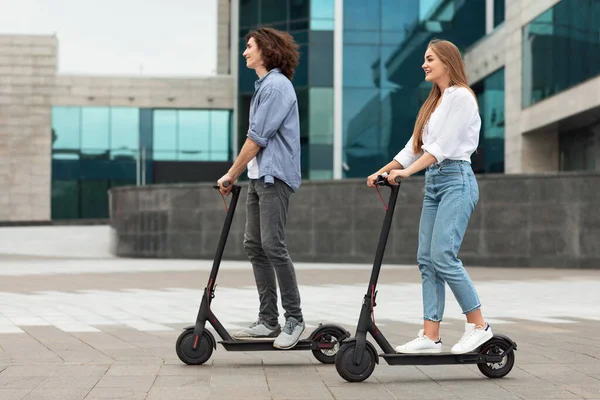 Cuplu de echitatie motorizat lovi cu piciorul scutere în oraș — Fotografie, imagine de stoc