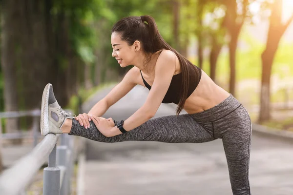 Dehnen im Freien. Sportlich asiatisch weiblich aufwärmen muskeln vor training im park — Stockfoto