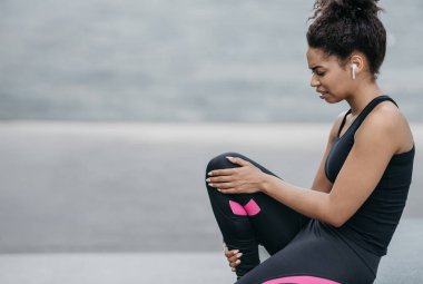 Kötü eğitim. Telsiz kulaklıklı üzgün kız yaralı bacağını tutuyor.