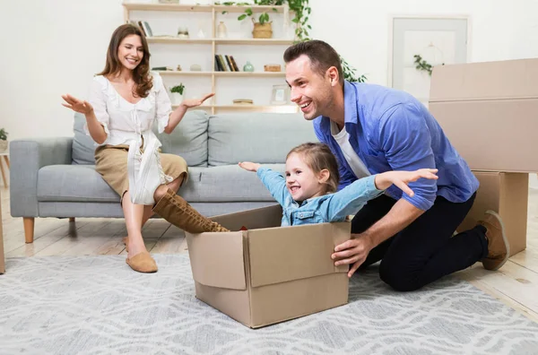 Счастливый отец катает дочь в коробке в новом доме — стоковое фото