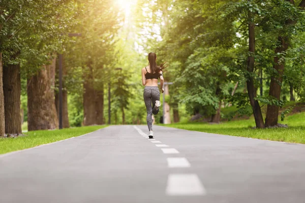 Sports Motivation. Back view of fit woman jogging in morning park — Stock Photo, Image