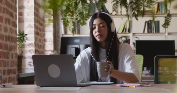 Asyalı öğrenci dizüstü bilgisayarda proje yazıyor ve kahvenin tadını çıkarıyor. — Stok video