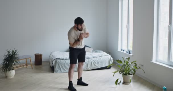 Joven barbudo entrenando en casa, girando sus caderas — Vídeos de Stock