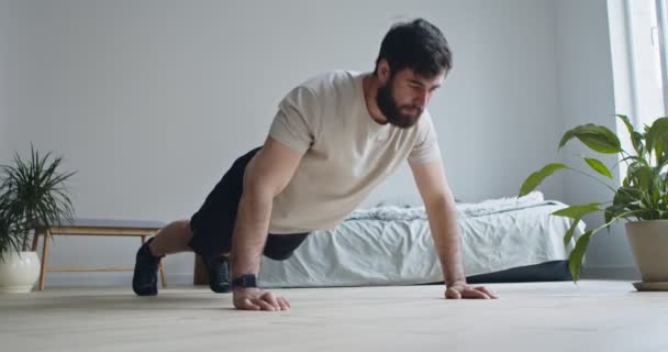 Bärtiger Typ macht Liegestütze im Schlafzimmer zu Hause — Stockvideo
