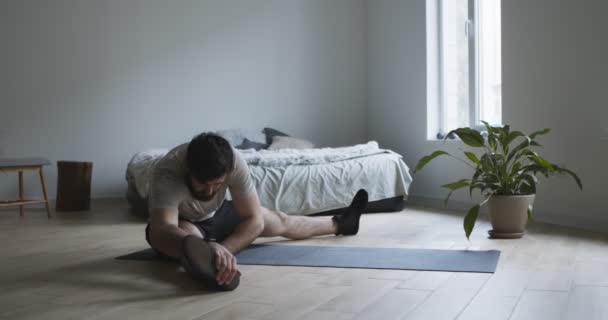 Jeune homme faisant étirement des jambes exercice à la maison — Video