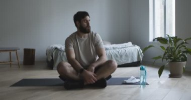 Yorgun adam su içiyor, evde antremandan sonra dinleniyor.