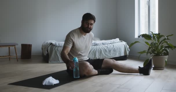 Уставший человек пьет воду из бутылки после тренировки — стоковое видео