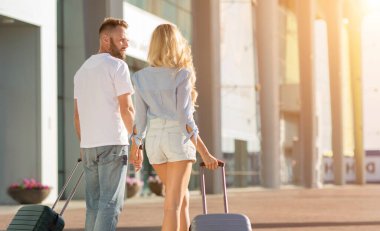 Mutlu çift havaalanında valizleriyle yürüyor.