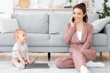 Dikkatsiz anne. Evde cep telefonuyla konuşan ve bebeğini görmezden gelen bir kadın.