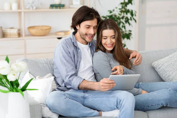 Casal jovem positivo usando tablet digital em casa — Fotografia de Stock