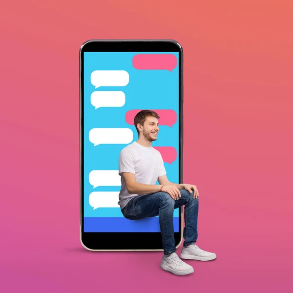 Chico alegre sentado en la pantalla del teléfono inteligente con burbujas sms — Foto de Stock