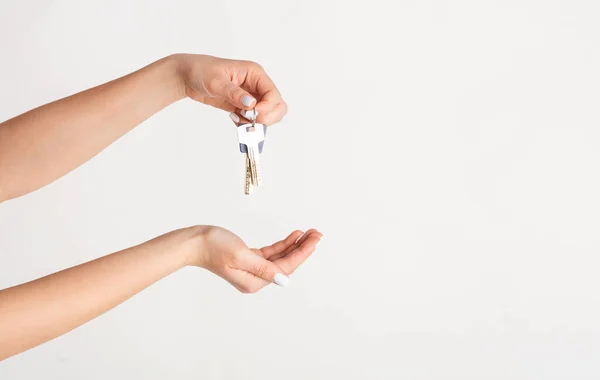 Primer plano de la mano femenina sosteniendo la llave de la casa sobre fondo blanco, espacio vacío —  Fotos de Stock