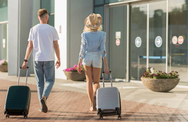 Havaalanı terminaline bavullarla yürüyen turistler
