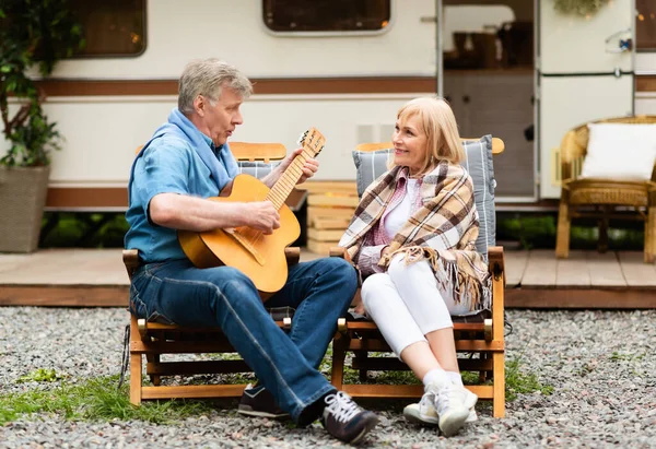 Romántico hombre mayor tocando la guitarra y cantando canción a su esposa cerca de autocaravana en el camping —  Fotos de Stock