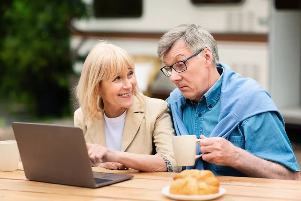 Szczęśliwa seniorka pokazująca coś mężowi na laptopie podczas kempingu na świeżym powietrzu — Zdjęcie stockowe