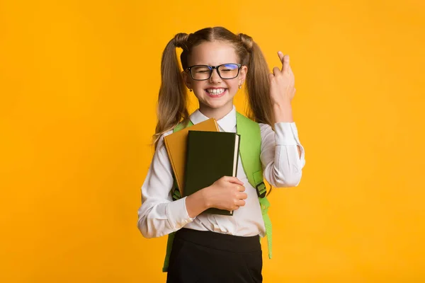 Schoolmeisje houden vingers gekruist voor geluk in school, Studio schot — Stockfoto