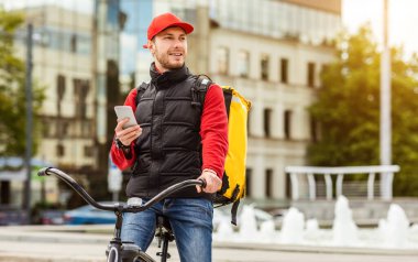 Kurye Cep Telefonu Kullanıyor. Yiyecek dağıtıyor. Bisiklet sürüyor.