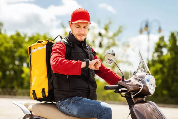 Courier Guy On Scooter Checking Time Delivering Food In City